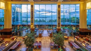A spacious indoor area with multiple dining tables and chairs, large windows offering a view of the cityscape, and a central column structure. - Swissotel The Bosphorus Istanbul (Istanbul)