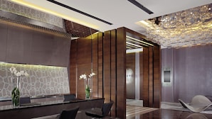 A modern reception area with a marble reception desk, two black chairs, a vase with white flowers, and a decorative ceiling light. - Swissotel The Bosphorus Istanbul (Istanbul)