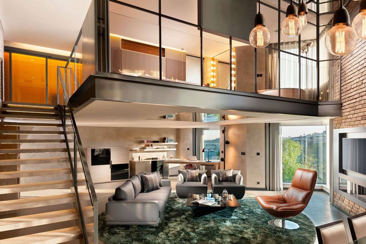 A modern living space with a staircase, a sofa set, a coffee table, and a leather chair.