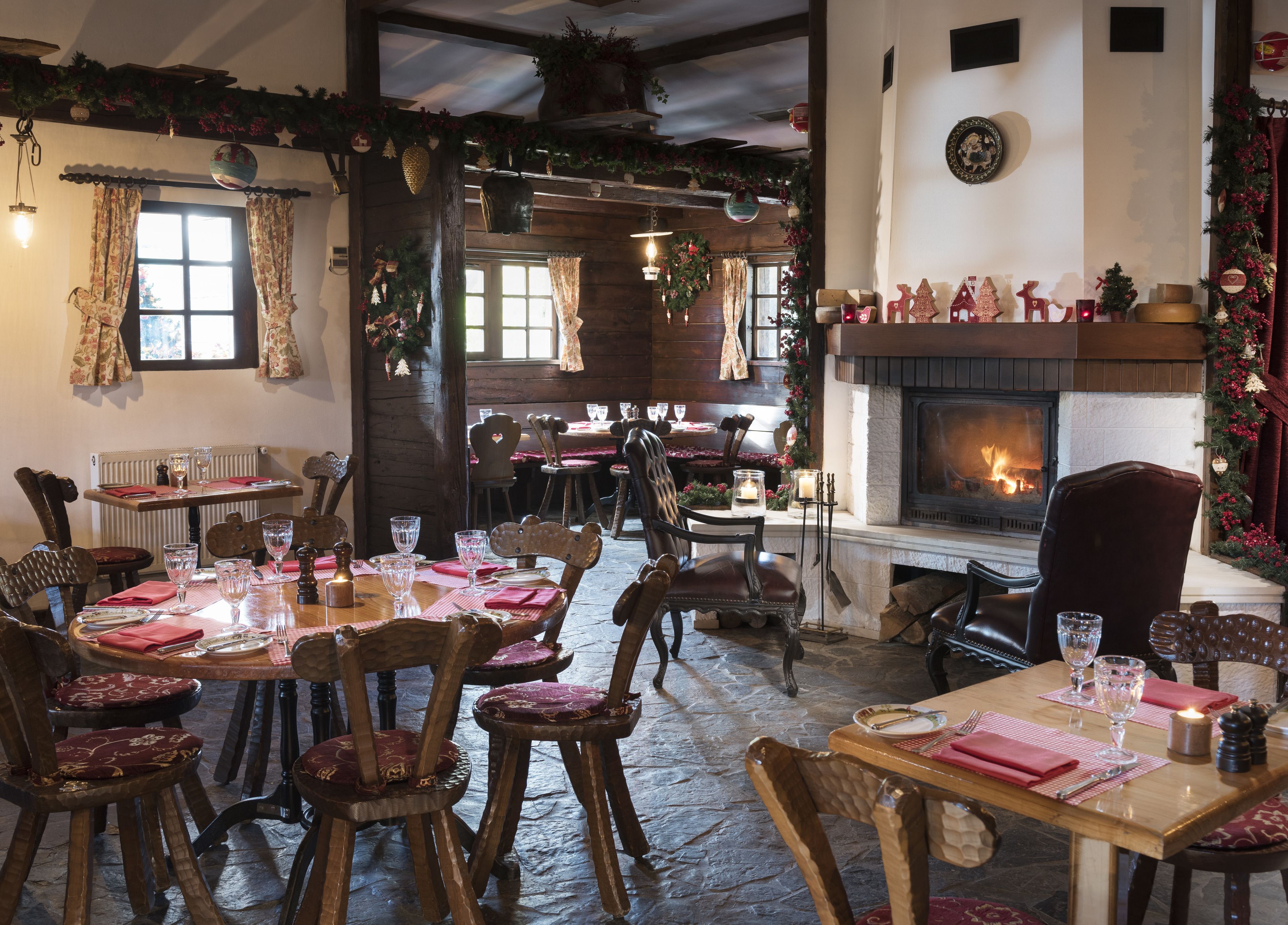 A cozy restaurant with wooden furniture, a fireplace, and festive decorations.