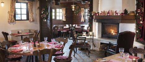Un restaurante acogedor con muebles de madera, chimenea y decoración festiva.