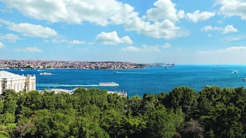 Eine Küstenstadt mit einem markanten historischen Gebäude, blauem Himmel und Blick auf das Meer mit Booten.