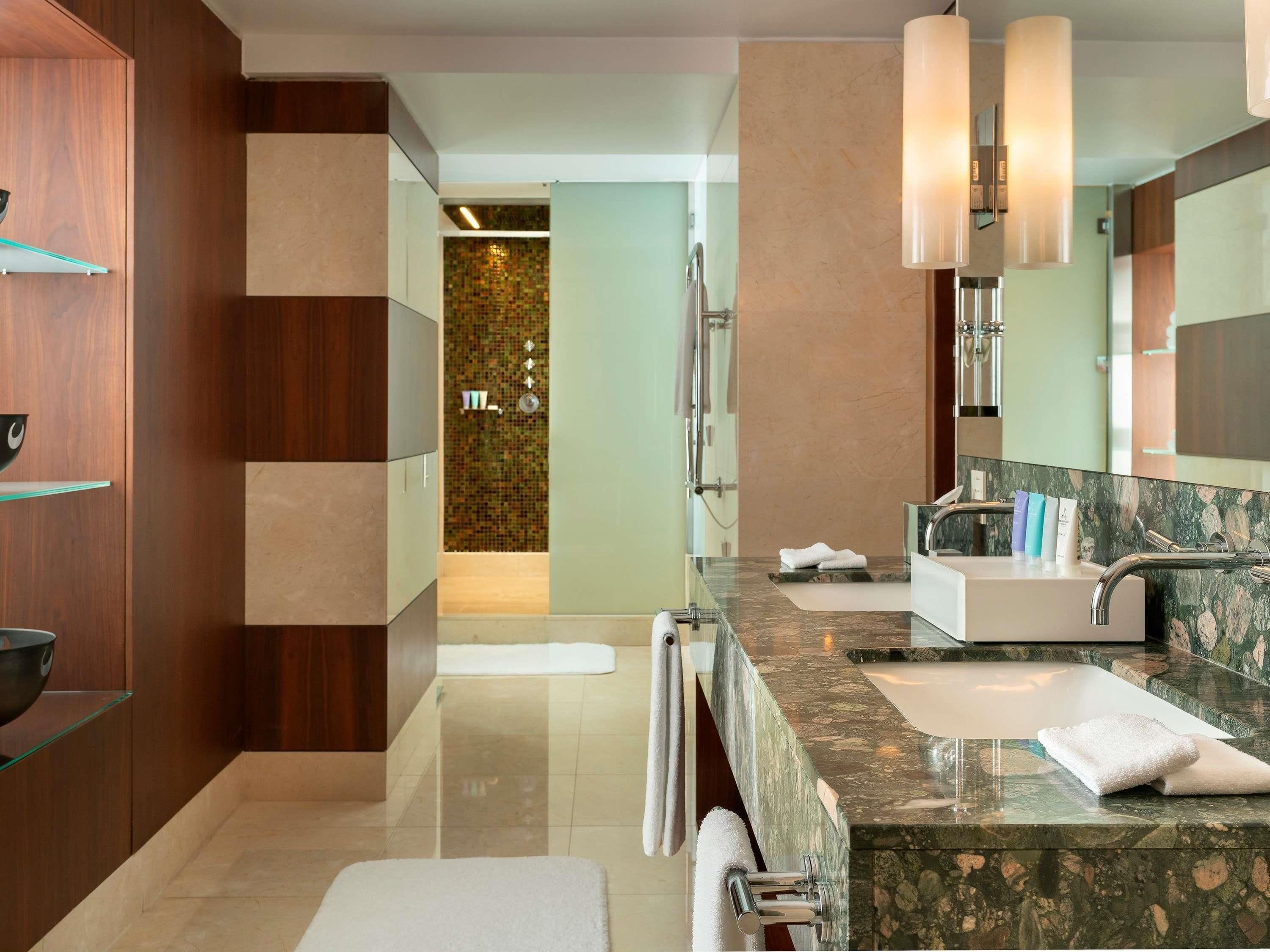 A modern bathroom with two sinks, a large mirror, and a shower area.