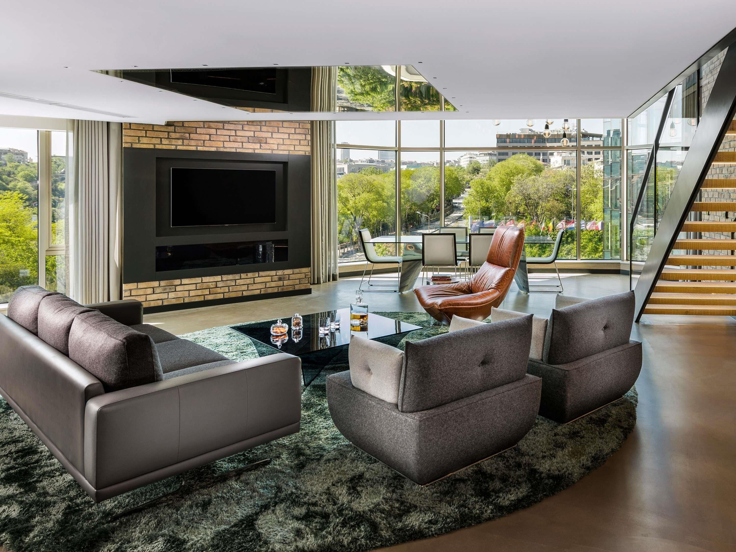 A modern living room with a fireplace, leather sofas, and a large TV.