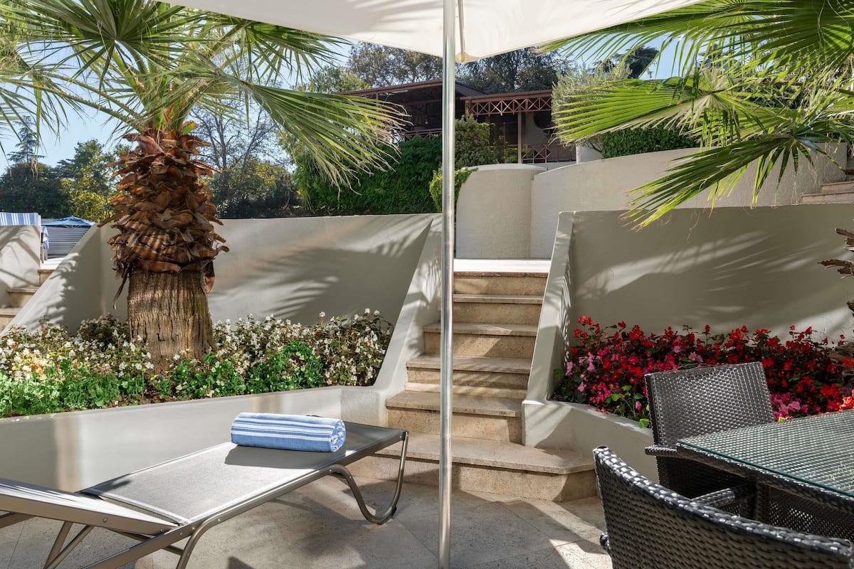 An outdoor seating area with a lounge chair, a table, and a large umbrella.