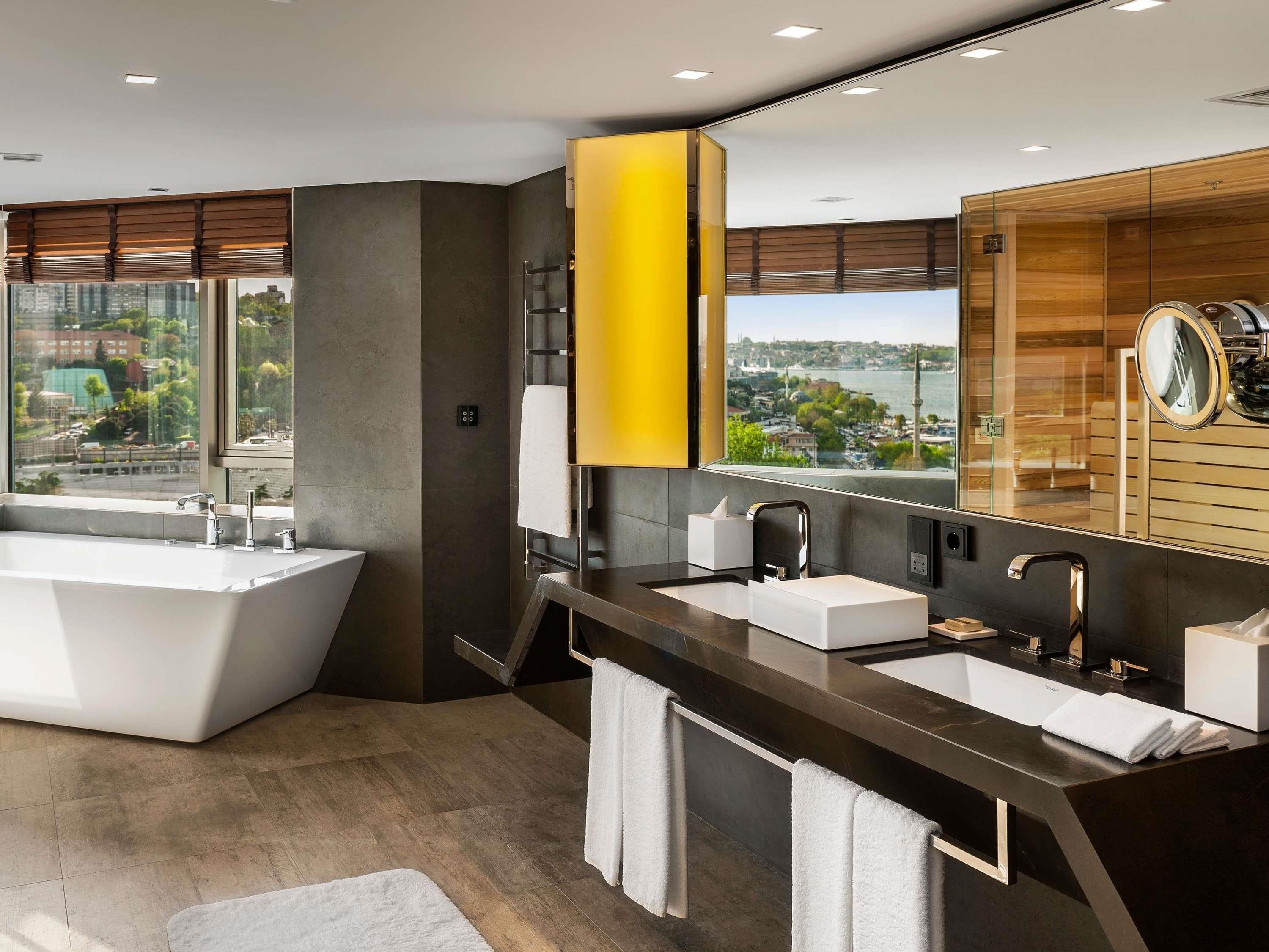 Une salle de bain moderne avec une grande baignoire, deux lavabos et un grand miroir.