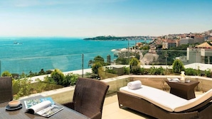 A terrace with wicker furniture, a glass balustrade, and a view of the sea and cityscape. - Swissotel The Bosphorus Istanbul (Istanbul)