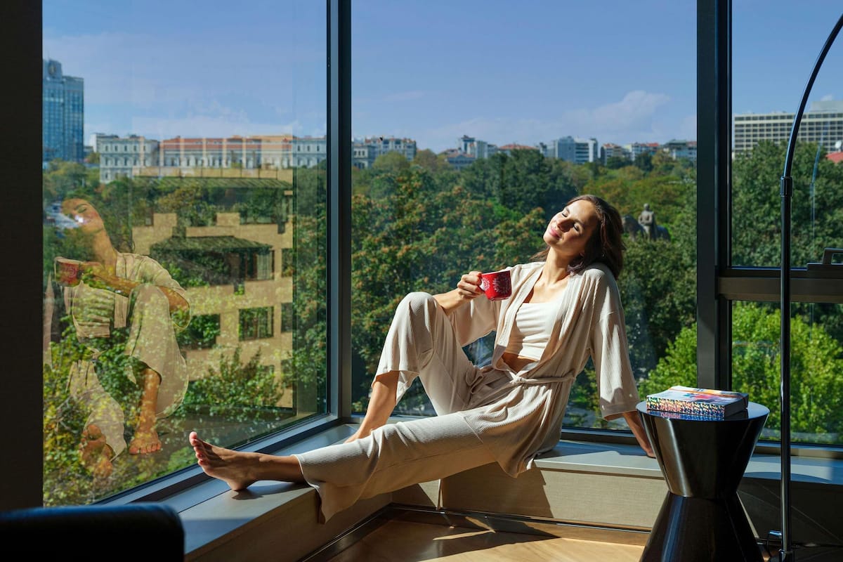 Una persona sentada junto a un ventanal con vistas a la ciudad.
