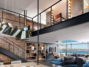 A modern interior with a staircase, a large bookshelf, a leather chair, and a view of the city. - Swissotel The Bosphorus Istanbul (Istanbul)