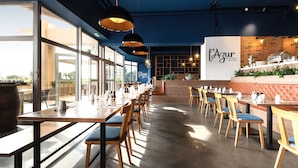 A restaurant interior with long tables, chairs, pendant lights, a brick wall, and a sign reading "l'Azur Bistro Nicolas". - Radisson Hotel Nice Airport (Nice)