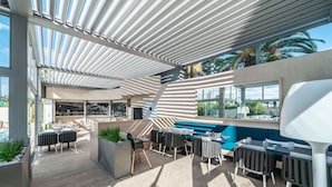 An outdoor patio area with modern seating, a pool, and large windows offering views of the surroundings. - Radisson Hotel Nice Airport (Nice)
