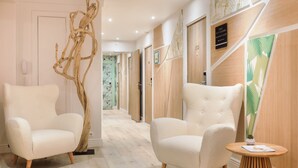 Un moderno vestíbulo de hotel con dos sillones cómodos, una escultura de madera y una pequeña mesa redonda con una planta.