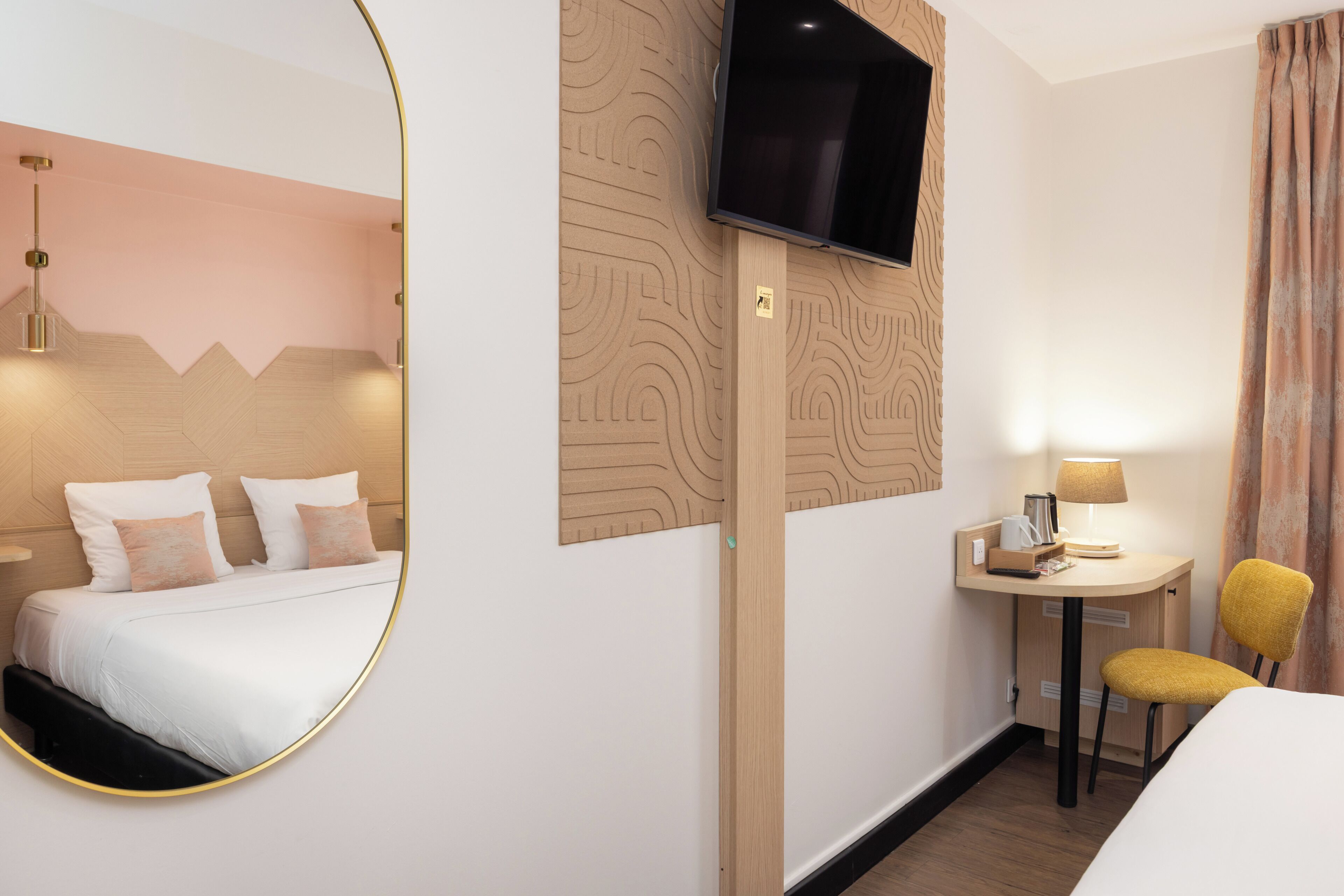 A hotel room with a bed, a desk, a chair, a TV, and a mirror.