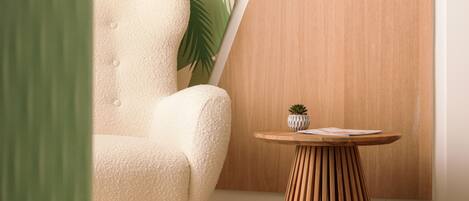Ein modernes Zimmer mit einem bequemen Sessel, einer Holzkommode und einem runden Holztisch mit einer kleinen Pflanze.