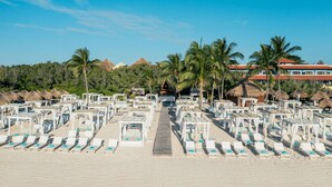 A beach resort with rows of sun loungers and thatched-roof structures.