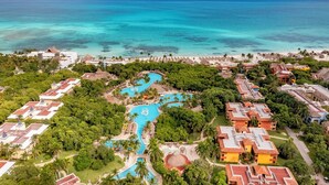 An aerial view of a resort with multiple buildings, a swimming pool, and a beach.