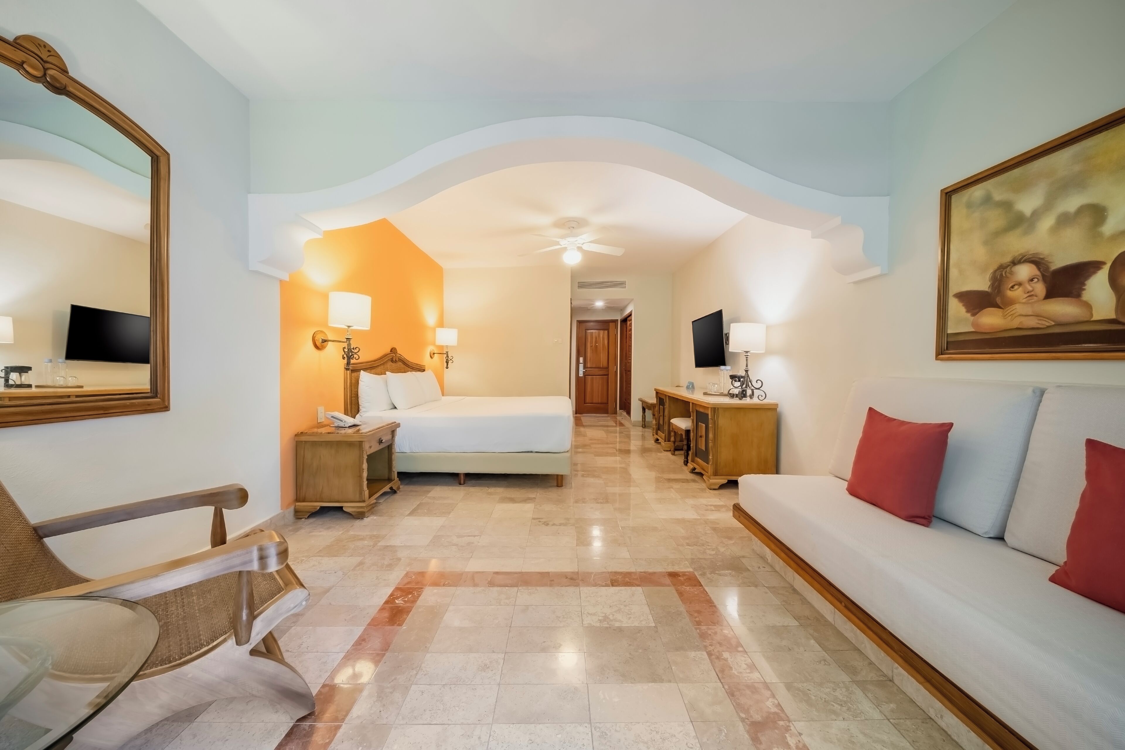 Una habitación de hotel con cama, sofá, sillón, escritorio y televisión.
