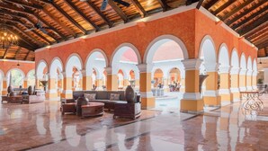 A spacious lobby with a tiled floor, multiple seating areas, and a high ceiling with wooden beams.