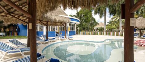 A pool area with lounge chairs and a thatched-roof structure.