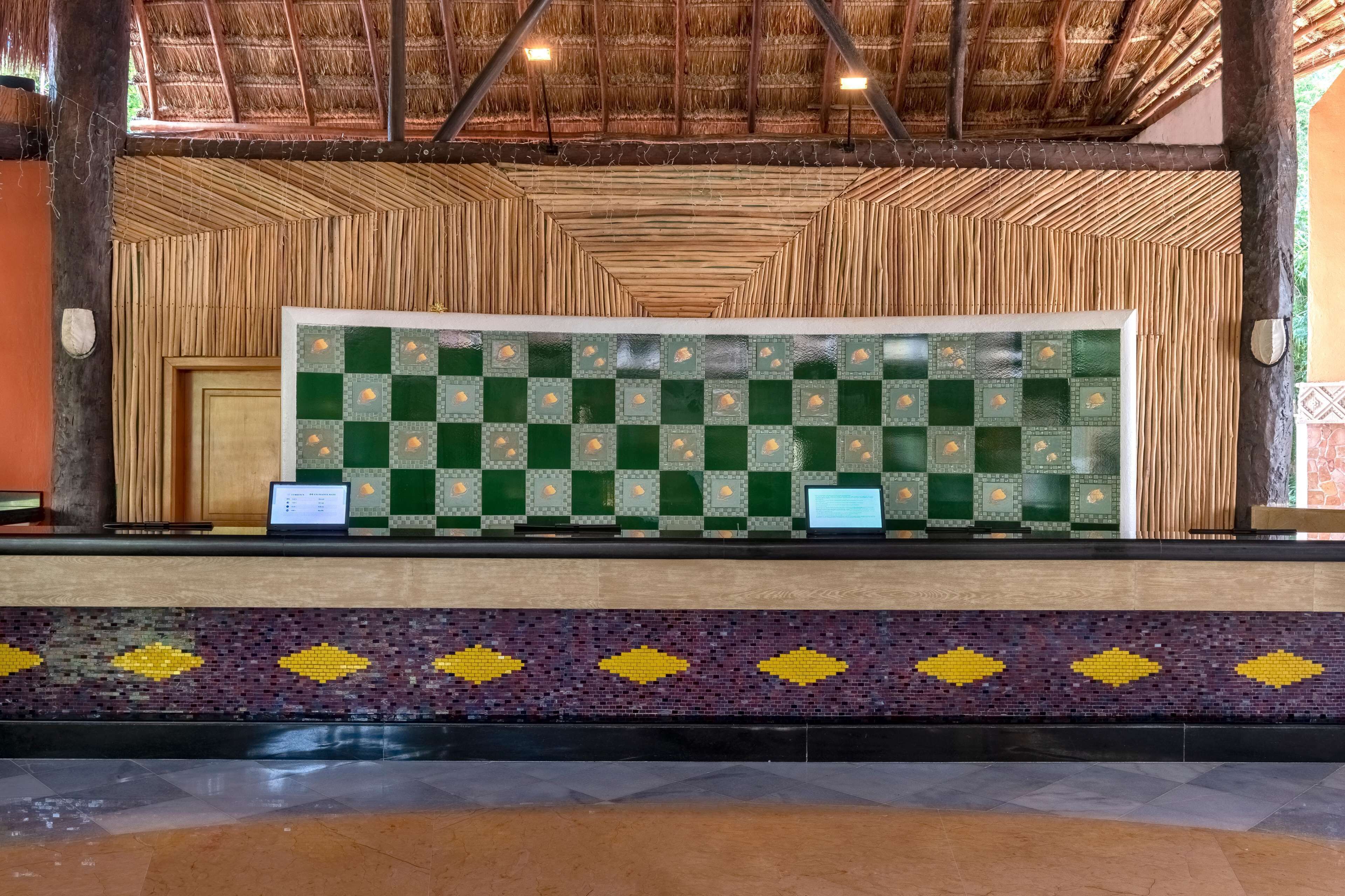 A reception area with a checkered tile wall, a wooden textured wall, and a patterned tile border.