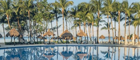 Una piscina al aire libre, sombrillas, sillones reclinables de piscina