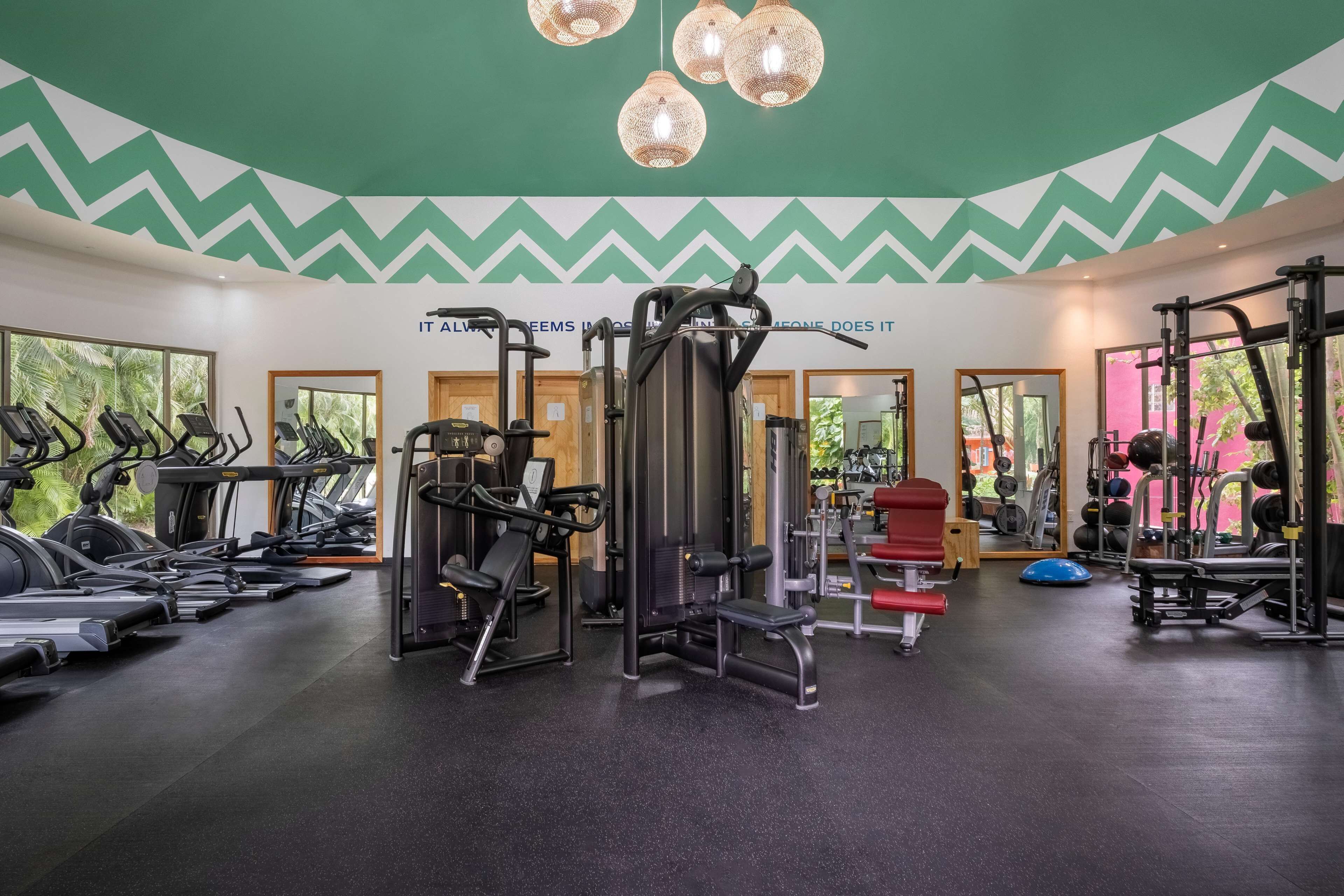 Ein Fitnessstudio mit Laufbändern, Kraftgeräten und einer Spiegelwand.