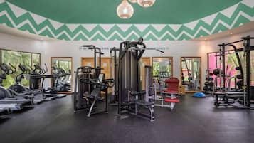 Ein Fitnessstudio mit Laufbändern, Kraftgeräten und einer Spiegelwand.