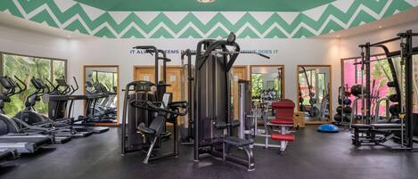 A gym with treadmills, weight machines, and a mirror wall.