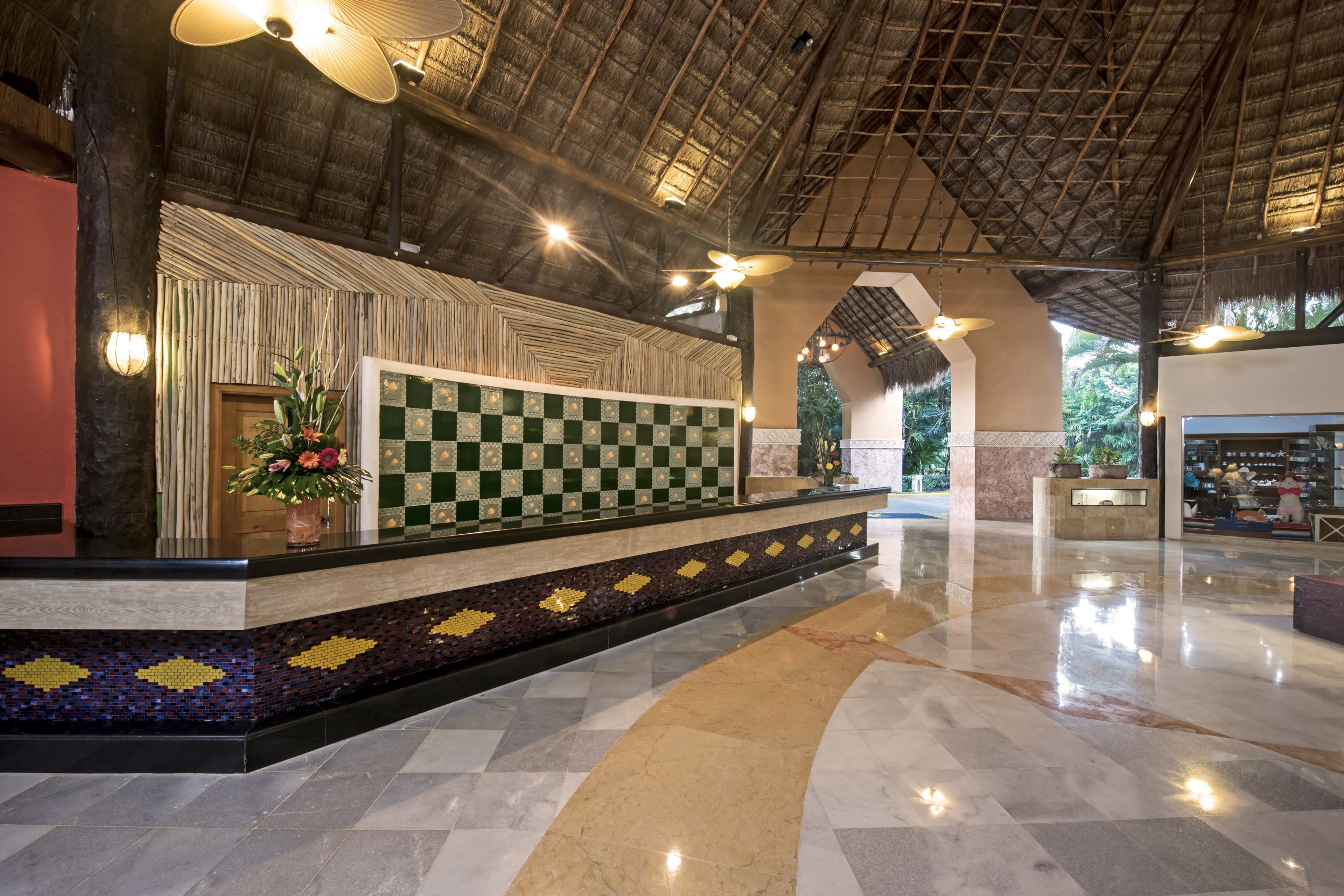 A reception area with a checkered floor, a decorative wall, and a ceiling fan.