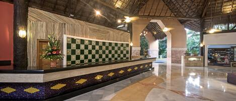 A reception area with a checkered floor, a decorative wall, and a ceiling fan.
