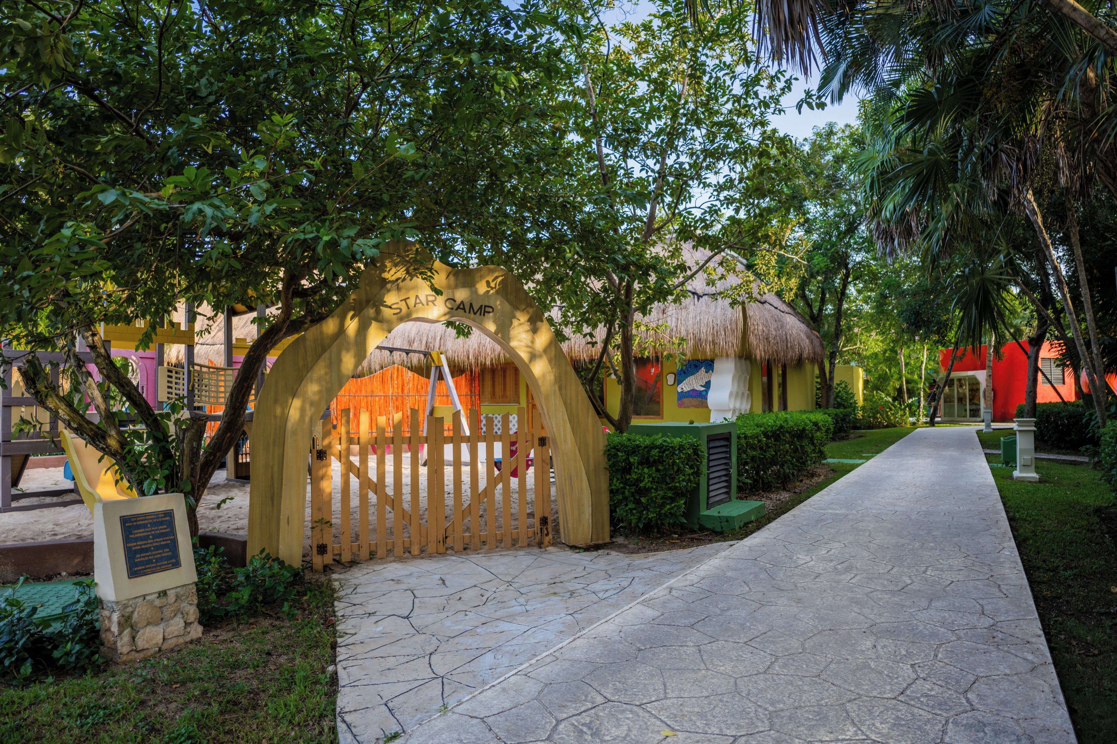A pathway leading to a thatched-roof structure labeled "Star Camp" with a wooden gate and a stone plaque.