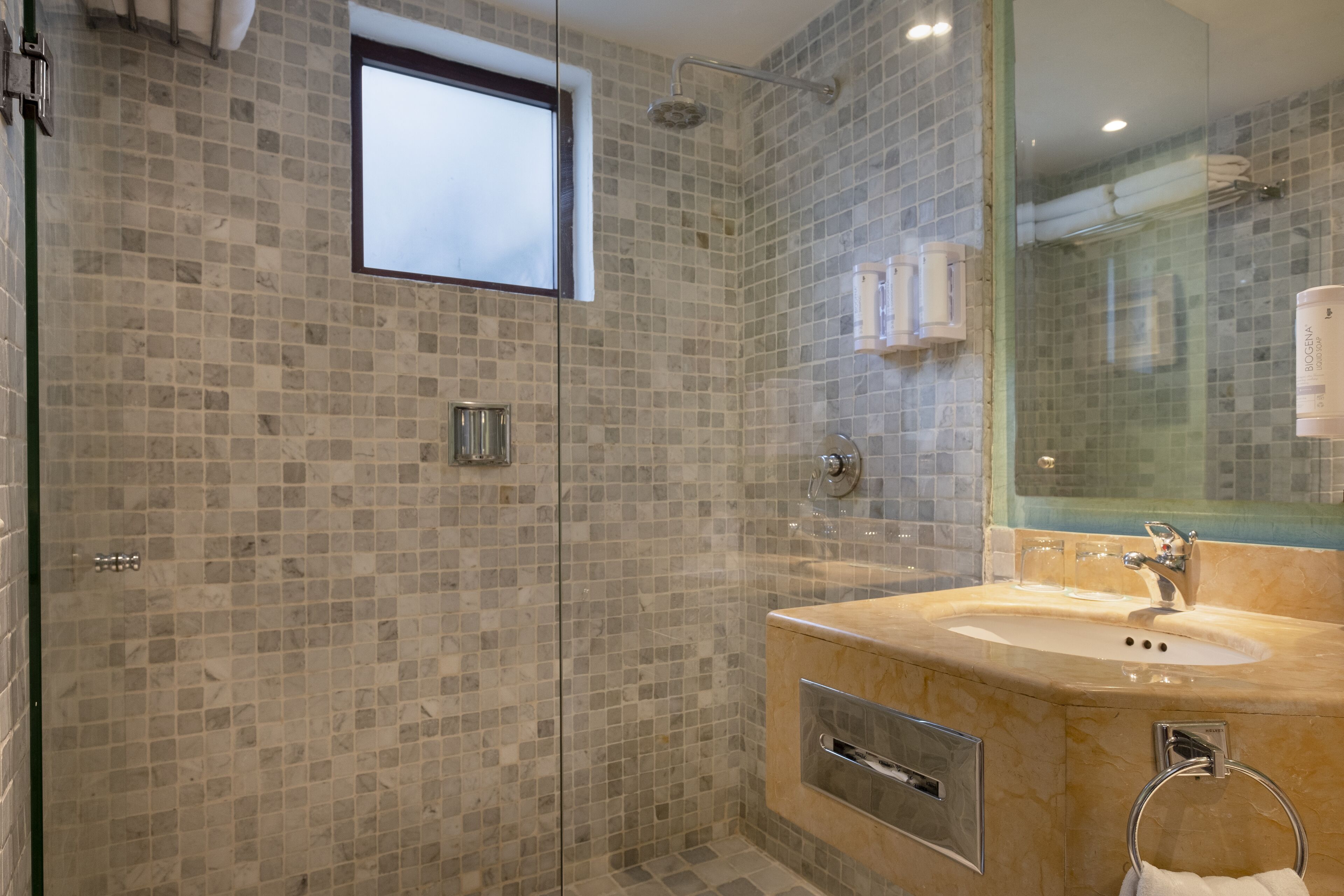 Une salle de bain moderne avec une douche à parois de verre, un grand miroir et un lavabo en marbre.