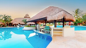 A resort pool area with thatched umbrellas, lounge chairs, and a bar. - Iberostar Waves Cozumel - All Inclusive (Cozumel)