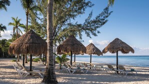 A beach with thatched umbrellas and white lounge chairs. - Iberostar Waves Cozumel - All Inclusive (Cozumel)
