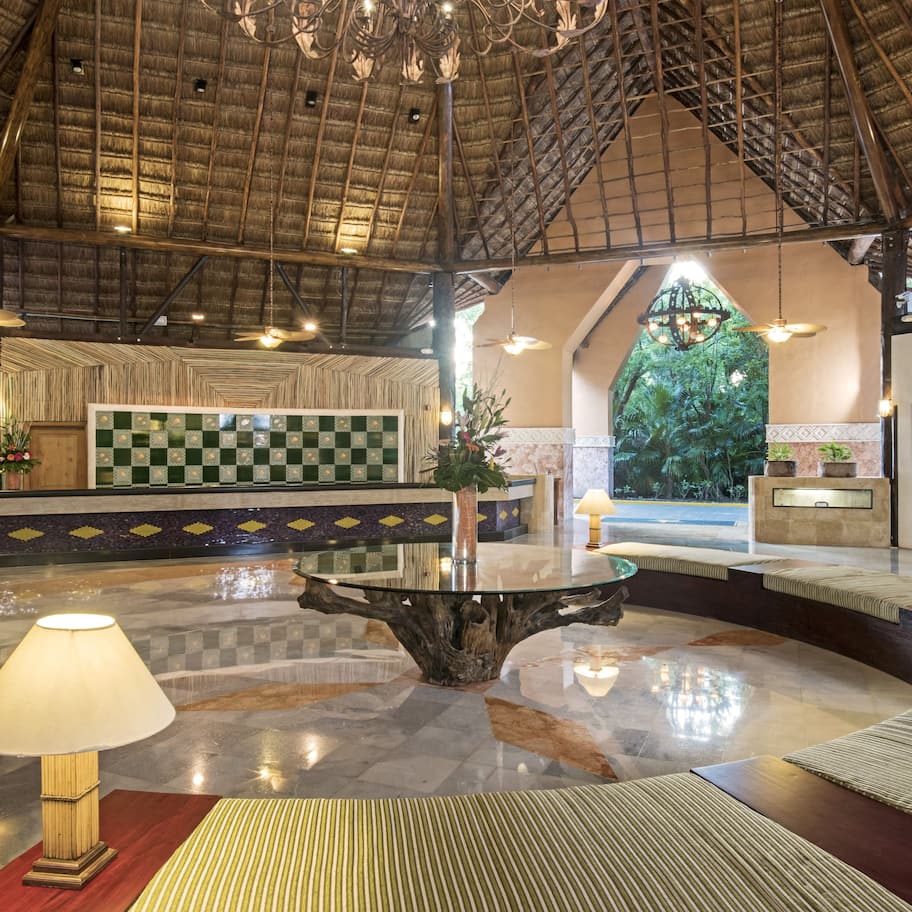 A lobby with a checkered floor, a central glass table, and a reception area with a green and white checkered wall.