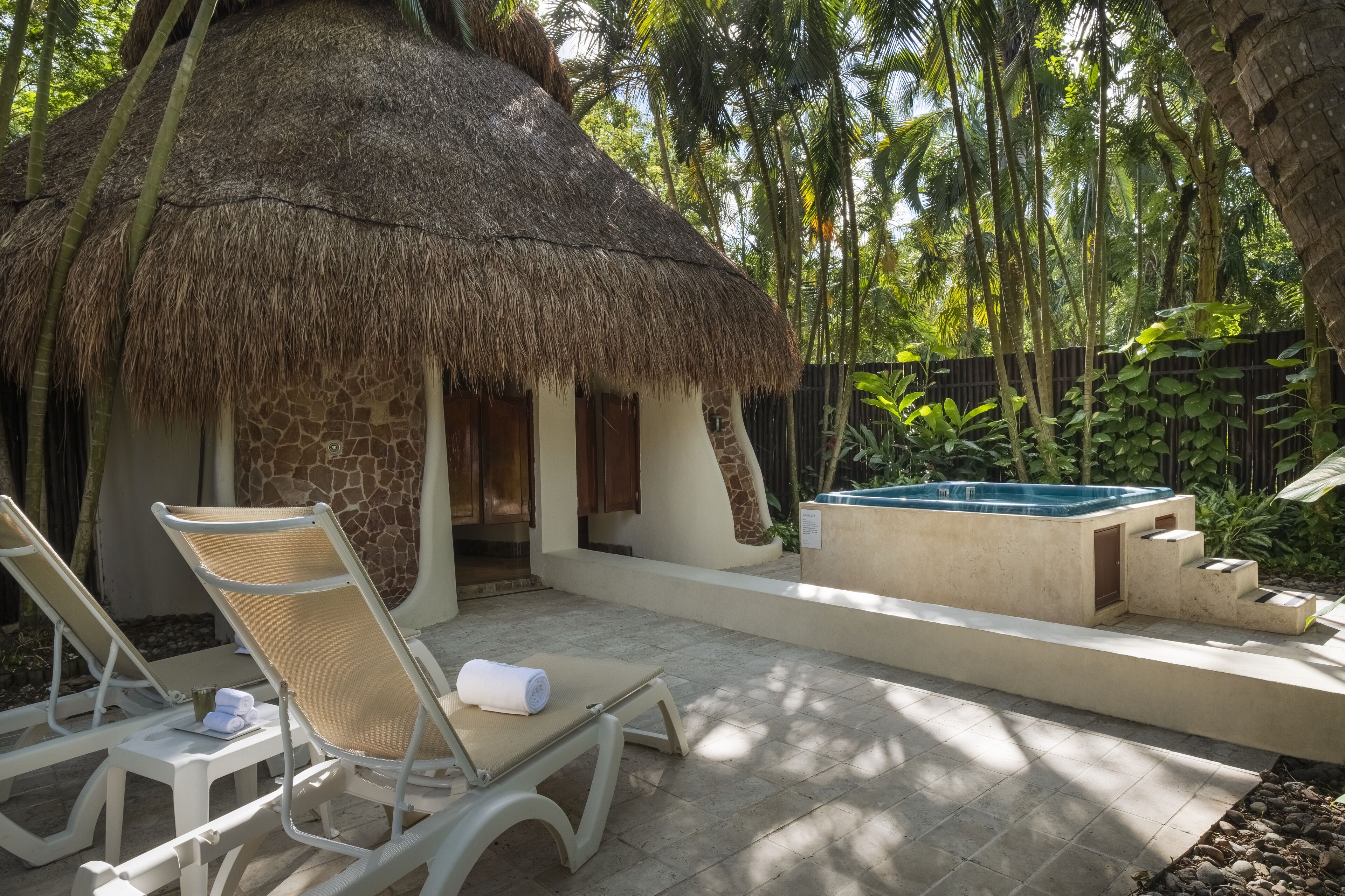 A thatched-roof structure with a pool and lounge chairs.