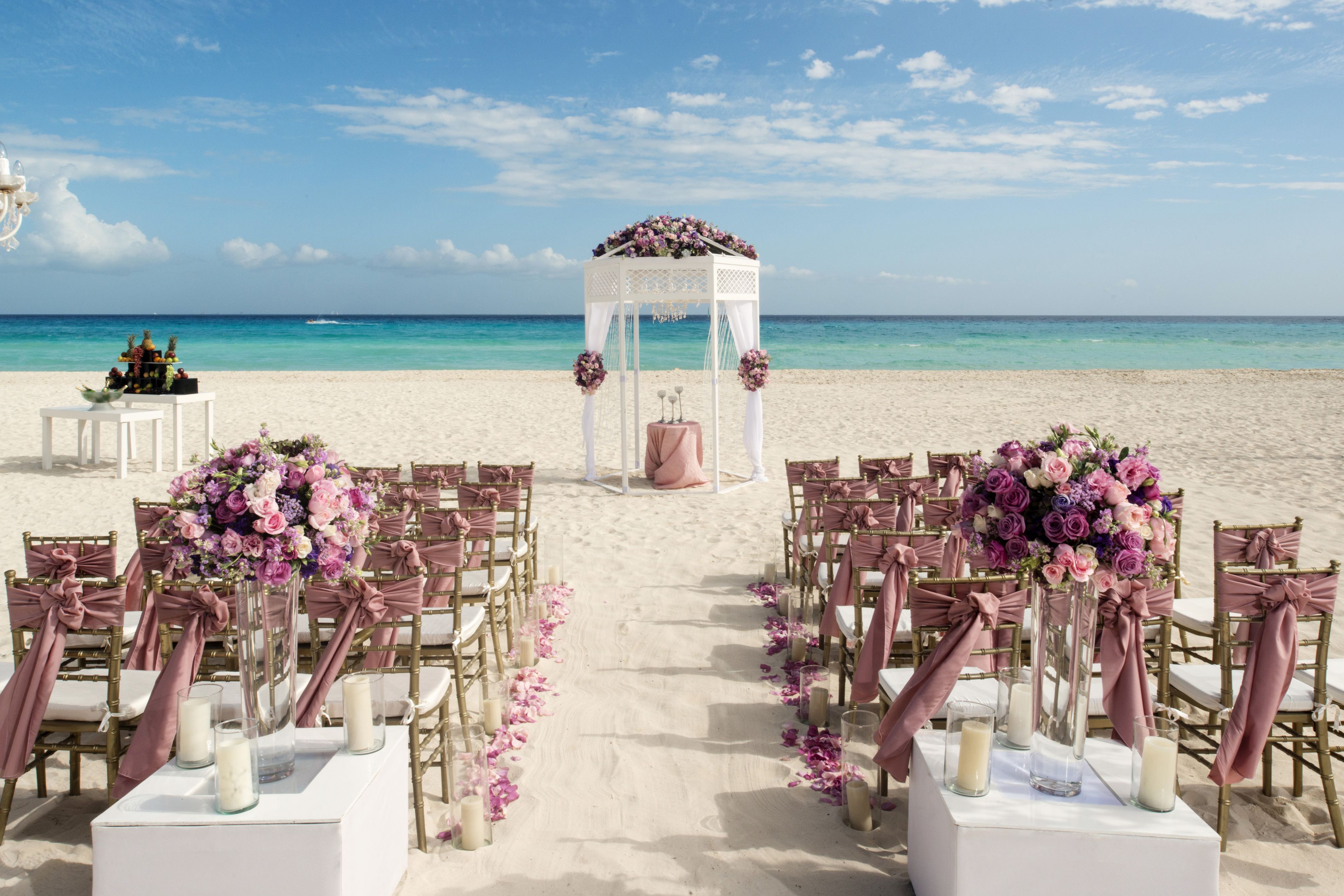Une cérémonie de mariage organisée sur la plage, avec une arche blanche et des décorations florales.