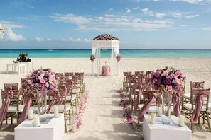 A beach wedding setup with a white arch and floral decorations.