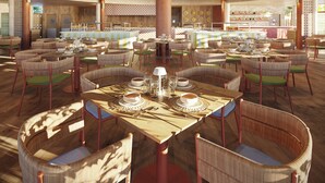 Un comedor espacioso con techos altos, muebles de mimbre y una barra central.