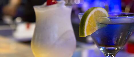 Two cocktails on a bar counter with a blurred background.