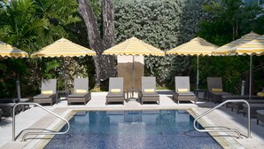 Una piscina con sillas de descanso y sombrillas a rayas.