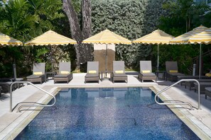 A swimming pool with lounge chairs and striped umbrellas. - The Rockley by Ocean Hotels (Rockley)