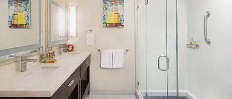 A modern bathroom with a glass-enclosed shower, a large mirror, and two wall-mounted sinks.
