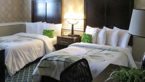 Une chambre d’hôtel avec deux lits, une table de chevet avec une lampe et une petite plante.
