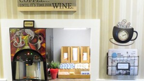 Une petite cuisine équipée d’une machine à café, d’une petite plante et d’un tapis décoré sur le thème du café.