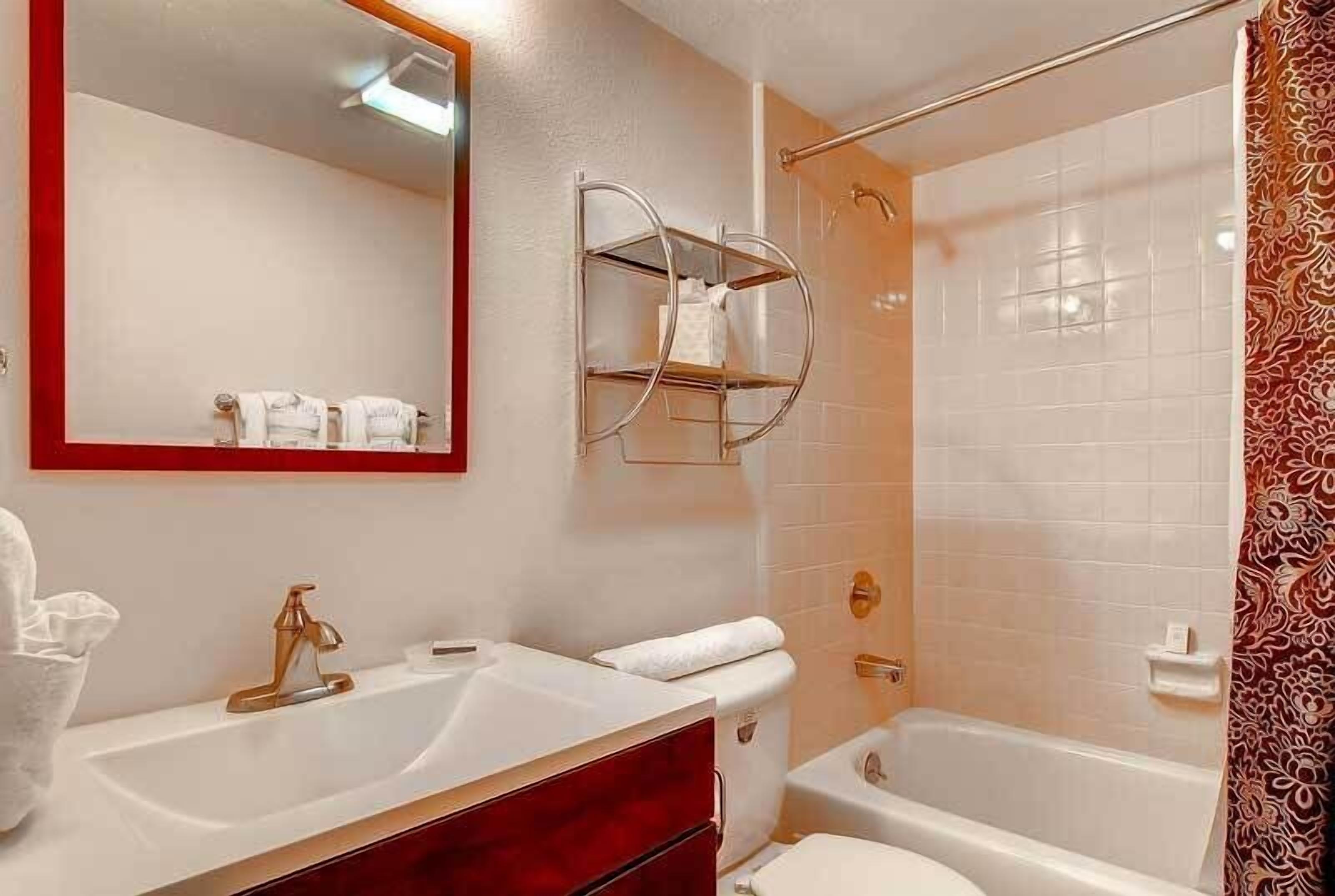 A bathroom with a white sink, a vanity, a toilet, and a shower area.