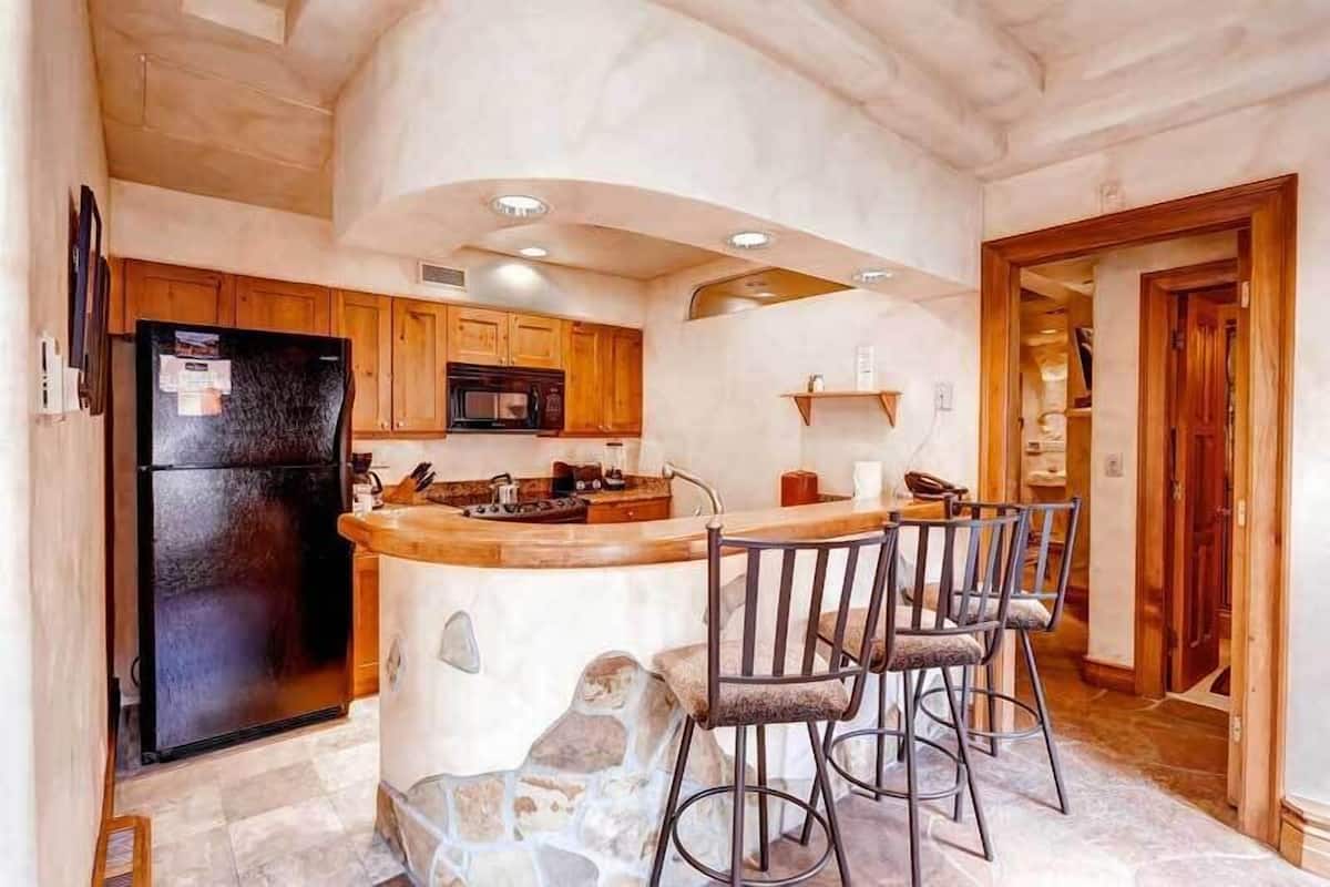 Una cocina con una isla central, armarios de madera, un refrigerador negro y un microondas.