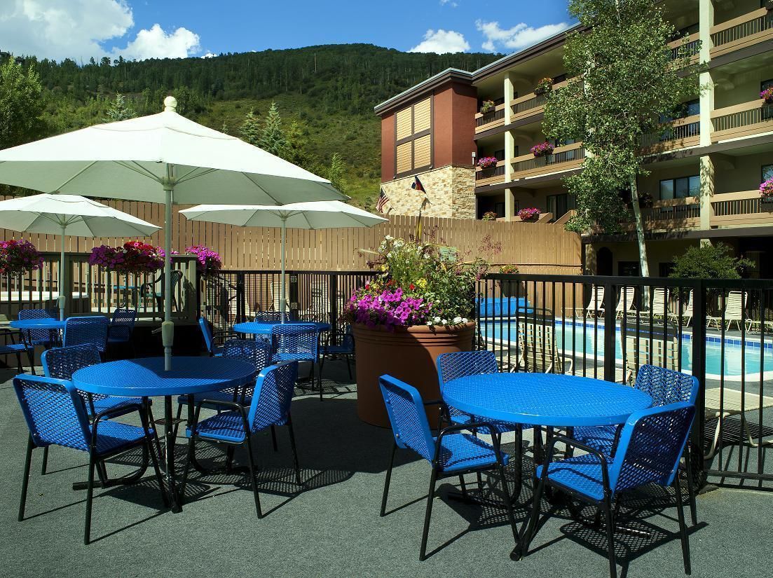 Outdoor seating with umbrellas, a pool, and a building with balconies.