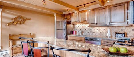 A kitchen with a large island, wooden cabinets, and a stone backsplash.