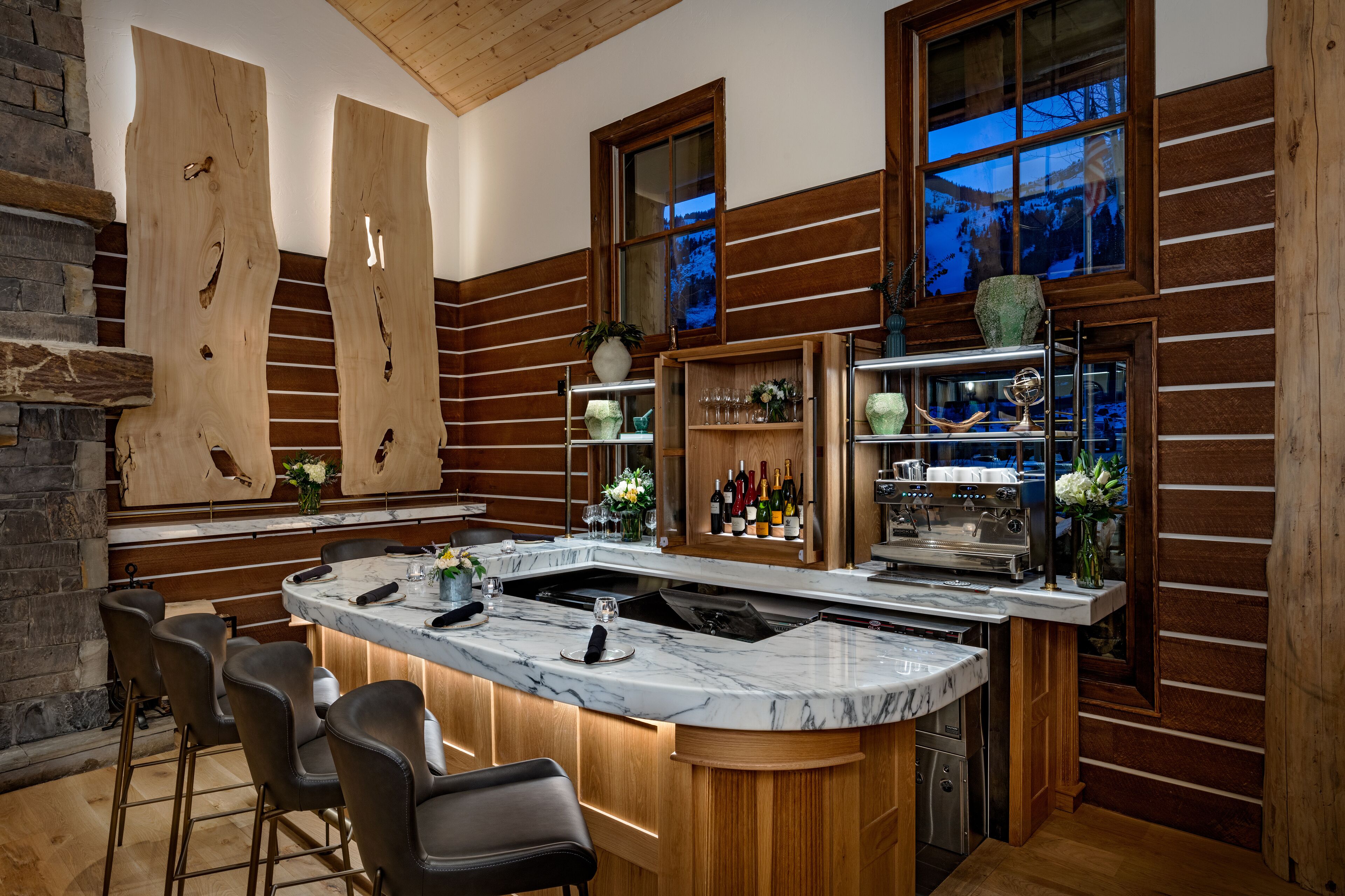 A modern kitchen with a marble countertop, wooden accents, and a bar area with wine bottles.